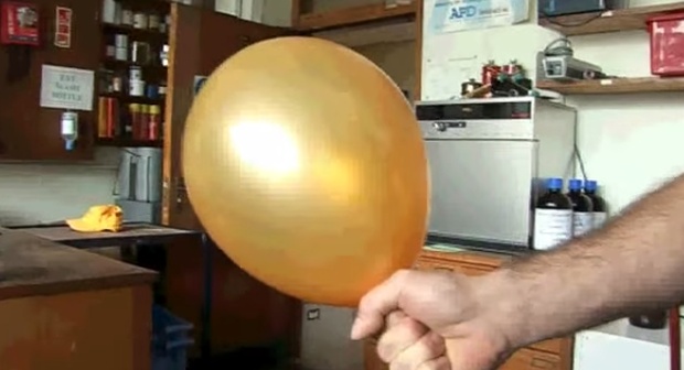 mão segurando balão amarelo com hélio