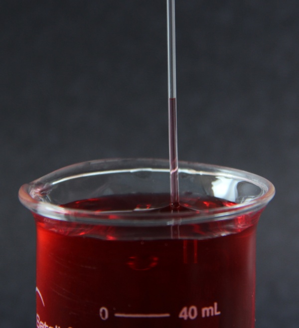 tubo capilar dentro de um bequer com liquido vermelho